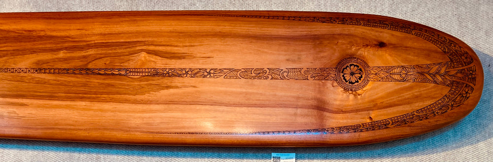 This image shows the top of the board where the most ornate detailing is found. A bold hibiscus is the emblem in the center, surrounded by ginger, waves, canoe sails and floral tribal.